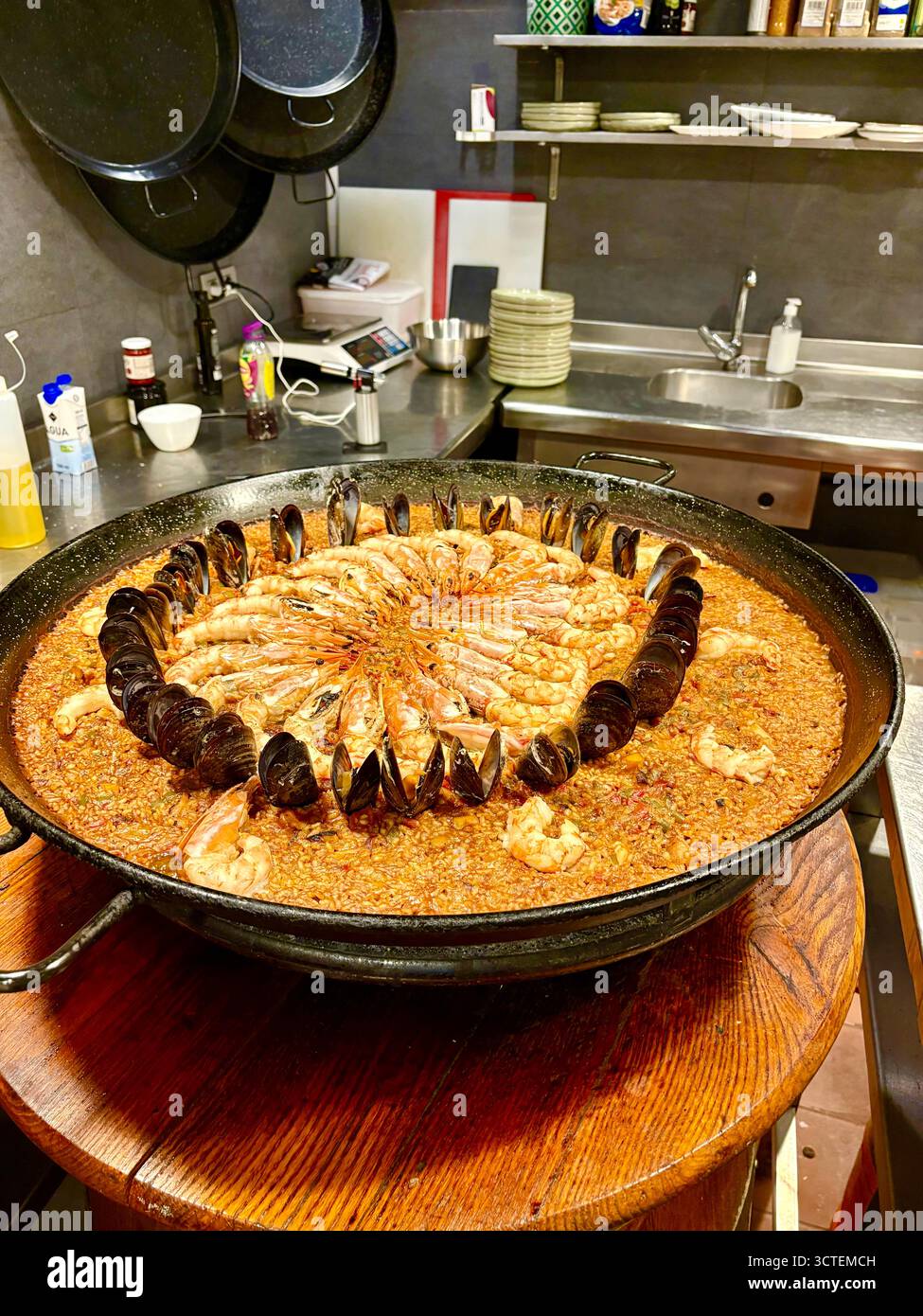 Cours de cuisine espagnole, apprenez à cuisiner la paella cours à Barcelone, paella fruits de mer mijote sur l'anneau de gaz avec moules et crevettes Banque D'Images