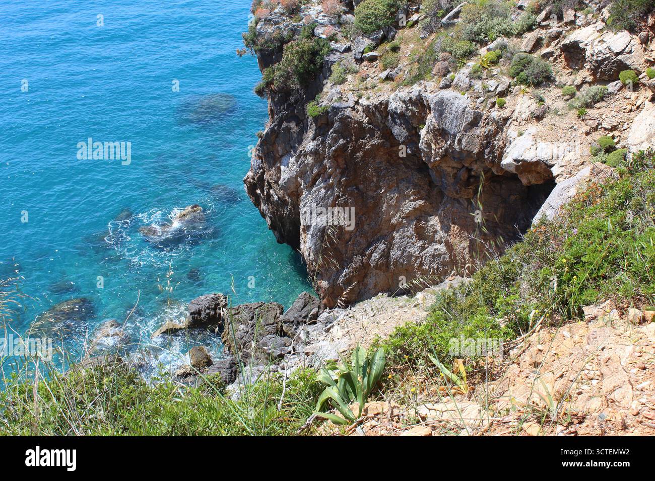 Falaise côtière méditerranéenne avec grotte marine et eau turquoise, rivage accidenté et océan bleu clair Banque D'Images