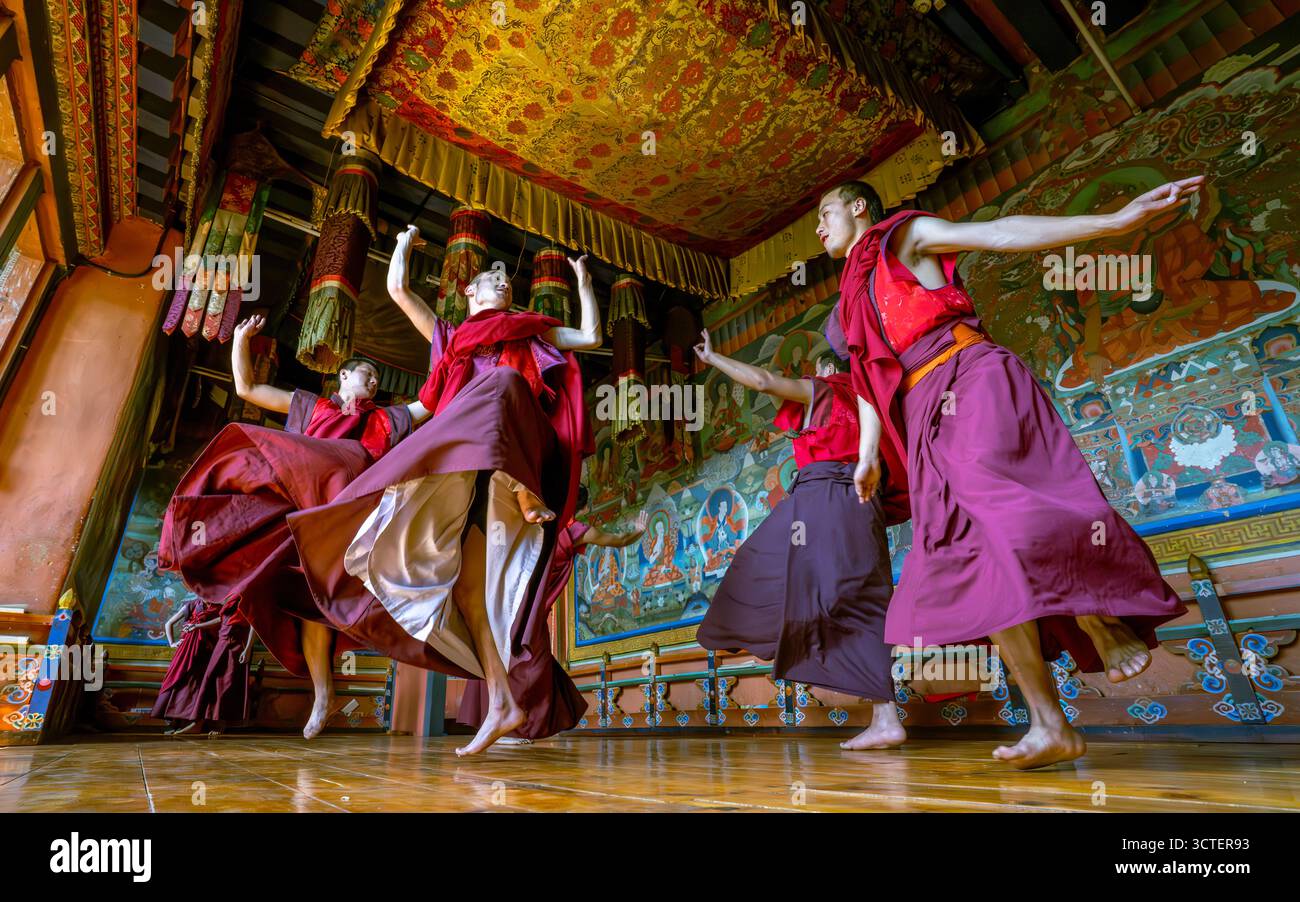 Jakar, Bhoutan - 24 septembre 2025 : vue de moines vêtus de robes rouges vibrantes dansent gracieusement dans les murs richement peints du sacré Jakar Dzong, un spectacle d'immersion culturelle. Banque D'Images