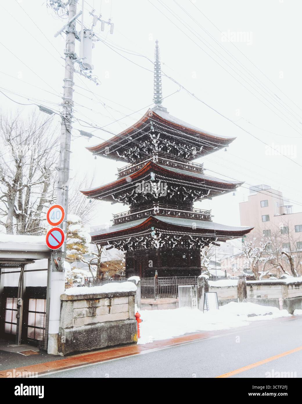 Vue sur la majestueuse pagode à trois niveaux, son bois sombre et ses accents rouges se distinguant sur la neige blanche et croustillante, créant une scène hivernale sereine, Tak Banque D'Images