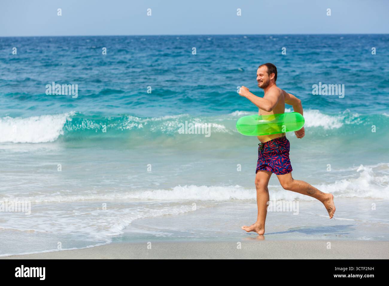 Heureux hipster barbu in s'amuser sur la plage à pied. L'homme drôle courir le long de mer surf et sauter à l'eau extérieure. Voyages en famille lifestyle, pis Banque D'Images