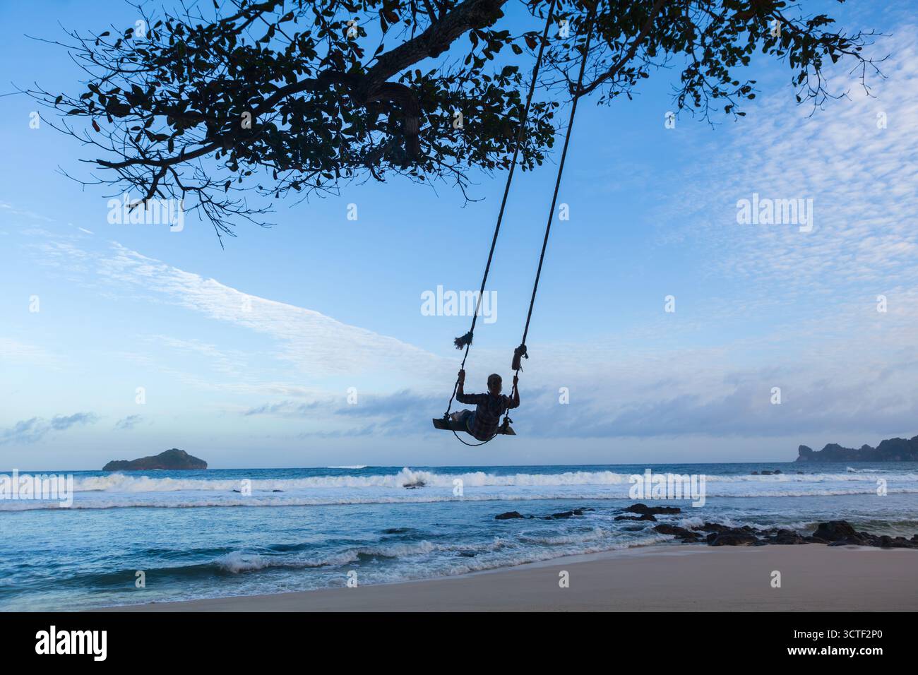 Happy Girl amusez-vous balancer haut dans l'air. Voler sur balançoire de corde sur la plage de la mer. Voyage aventure sur l'île tropicale paradisiaque. Style de vie familial Banque D'Images