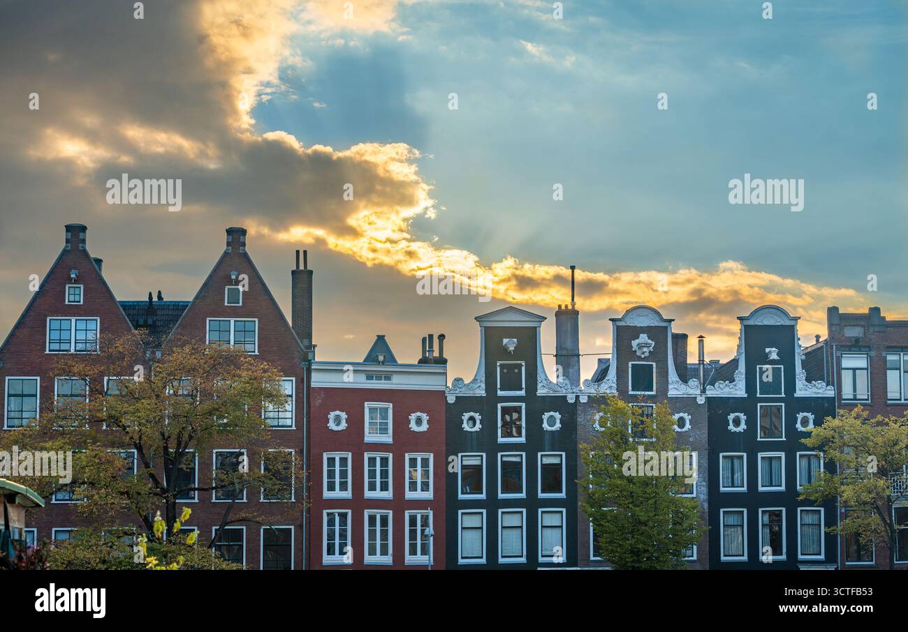 Paysage urbain d'Amsterdam, maisons de canal hollandaises traditionnelles contre le ciel coloré du coucher du soleil Banque D'Images