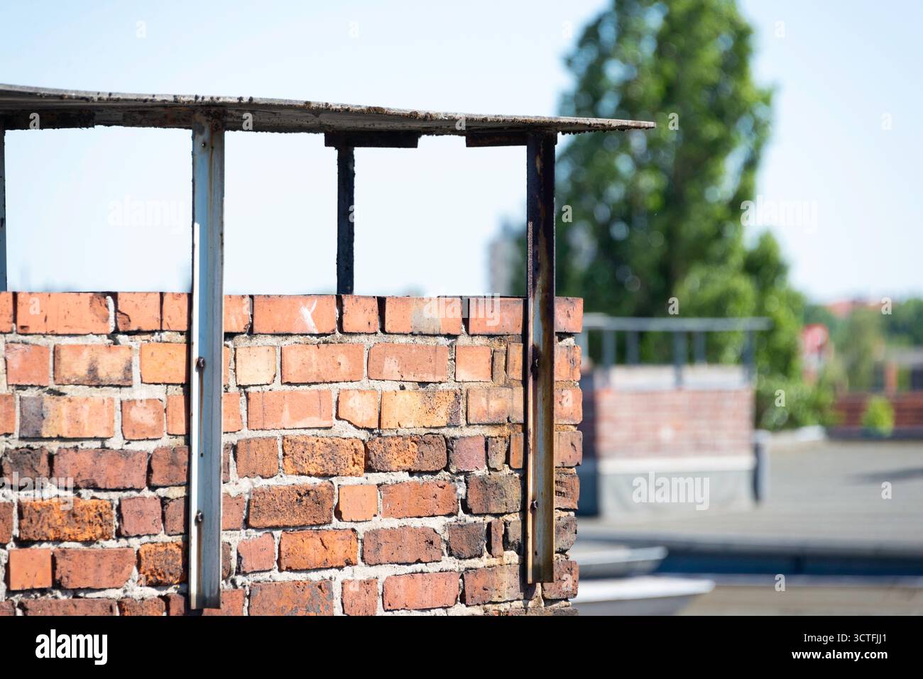 Un gros plan détaillé d'une cheminée en brique altérée sur un toit ensoleillé de Berlin. La faible profondeur de champ met en évidence la texture et crée une zone urbaine floue Banque D'Images