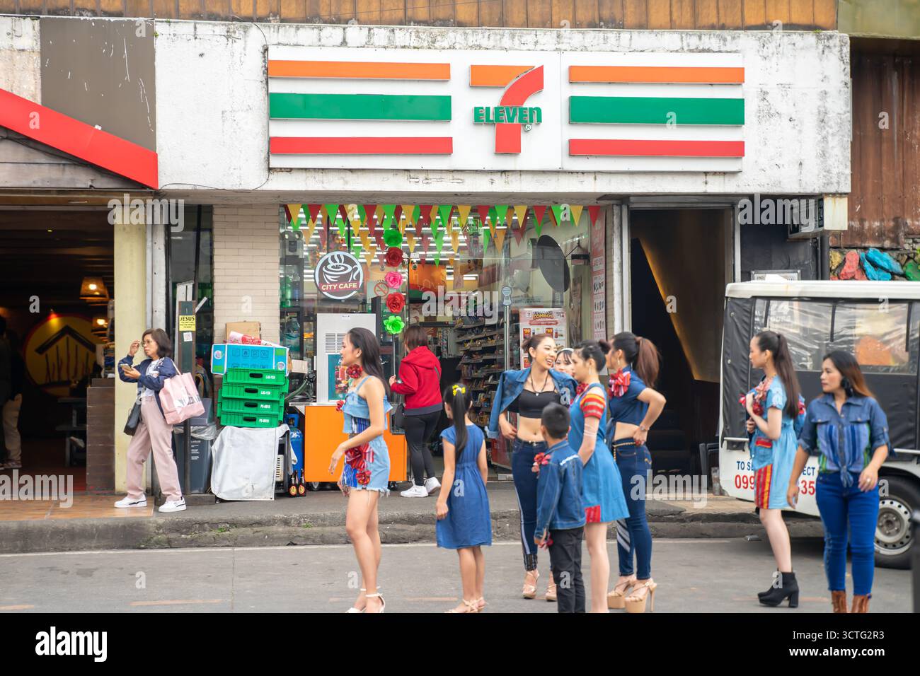 Participantes au défilé de mode féminin devant le dépanneur 7-Eleven, Baguio, Philippines Banque D'Images