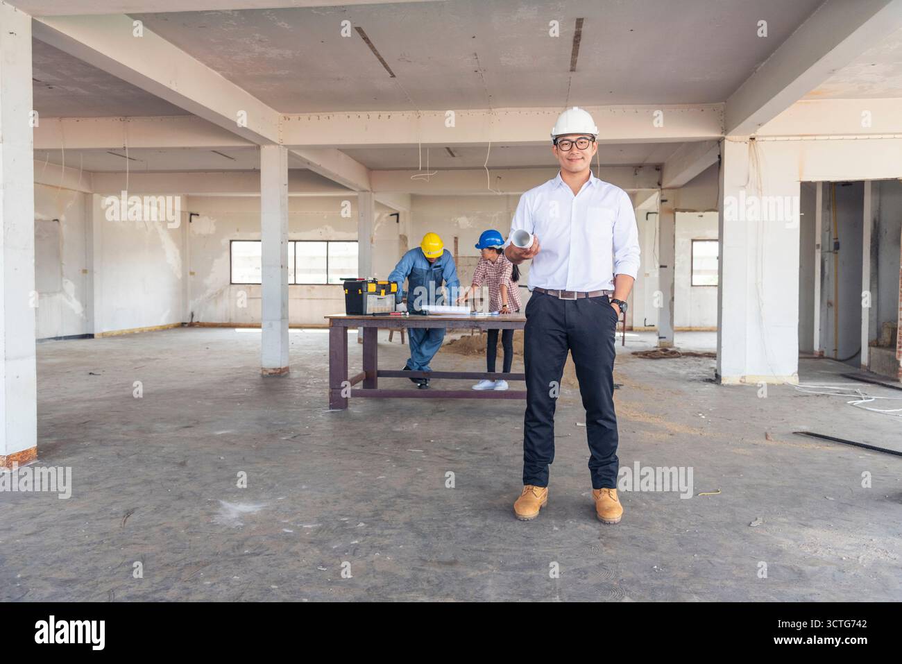 Ingénieur de construction TeamWork Safety suit Trust Team tenant l'équipement de sécurité de casque de sécurité blanc jaune sur le chantier de construction. HardHat Protect He Banque D'Images