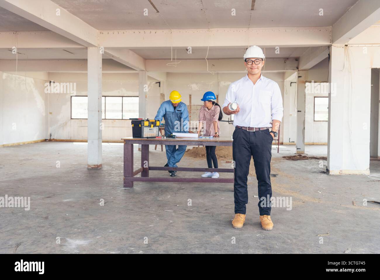 Ingénieur de construction TeamWork Safety suit Trust Team tenant l'équipement de sécurité de casque de sécurité blanc jaune sur le chantier de construction. HardHat Protect He Banque D'Images
