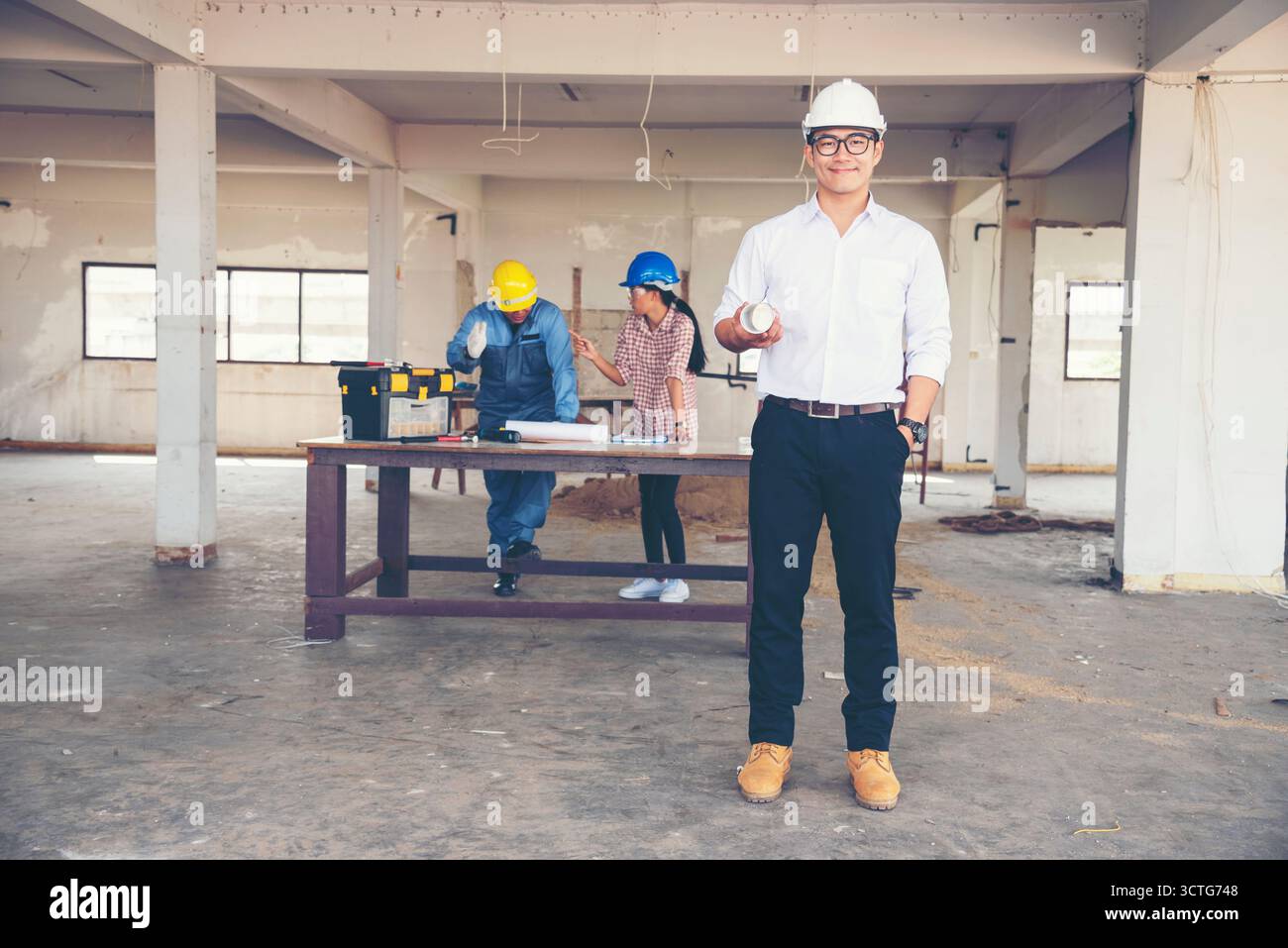 Ingénieur de construction TeamWork Safety suit Trust Team tenant l'équipement de sécurité de casque de sécurité blanc jaune sur le chantier de construction. HardHat Protect He Banque D'Images
