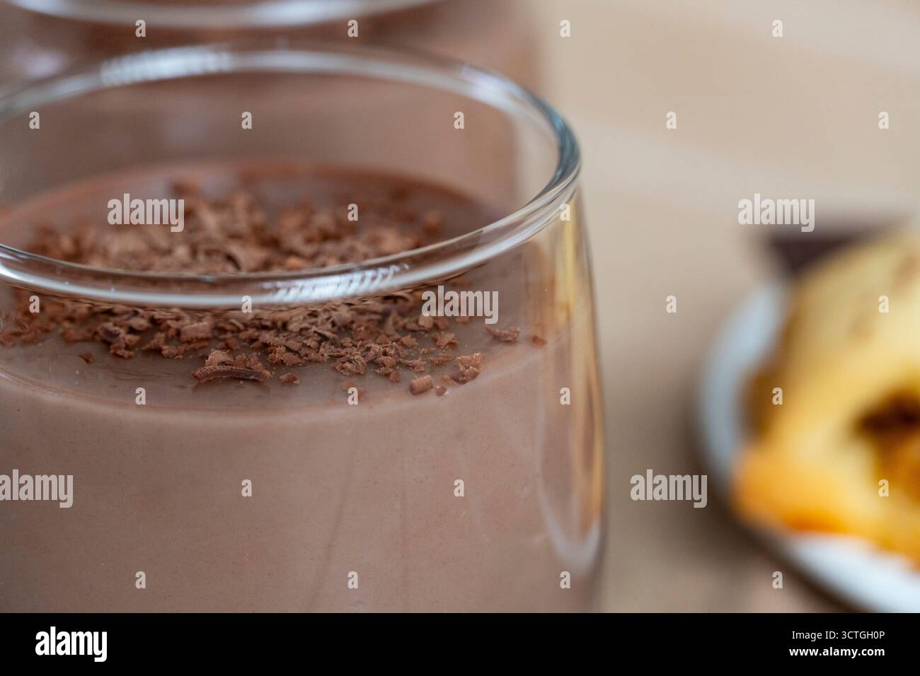 Délicieux biscuits faits maison servis avec du pudding au chocolat dans des tasses en verre, surmonté de chocolat noir râpé. Composition de dessert confortable sur table en bois Banque D'Images