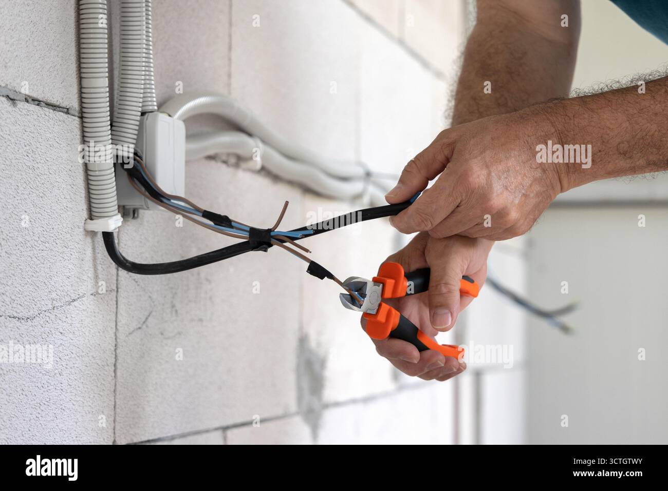 Électricien, réparateur travaillant à l'installation d'une installation électrique sur un chantier de construction d'une maison neuve Banque D'Images