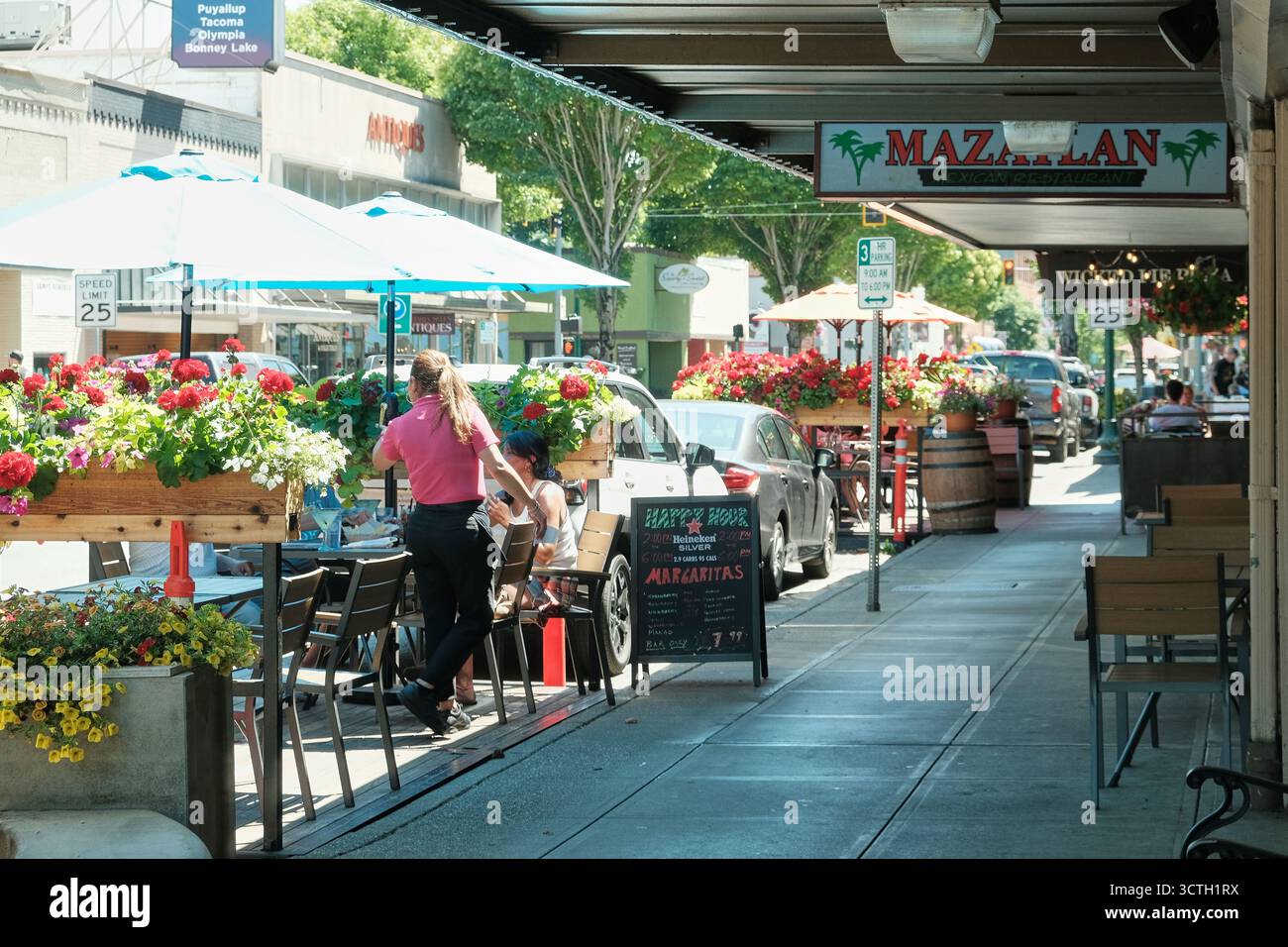 Puyallup WA USA, 26 juillet 2025 - tables de café dans la rue, clôtures décorées de fleurs. Café d'été sur la rue Puyallup Banque D'Images