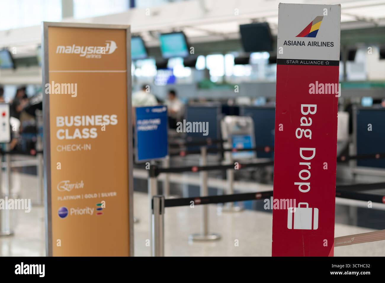 Hong Kong - 20 septembre 2025 : des panneaux adjacents marquent le comptoir dépose bagages Asiana Airlines et les comptoirs d'enregistrement de la classe affaires Malaysia Airlines sur le Banque D'Images