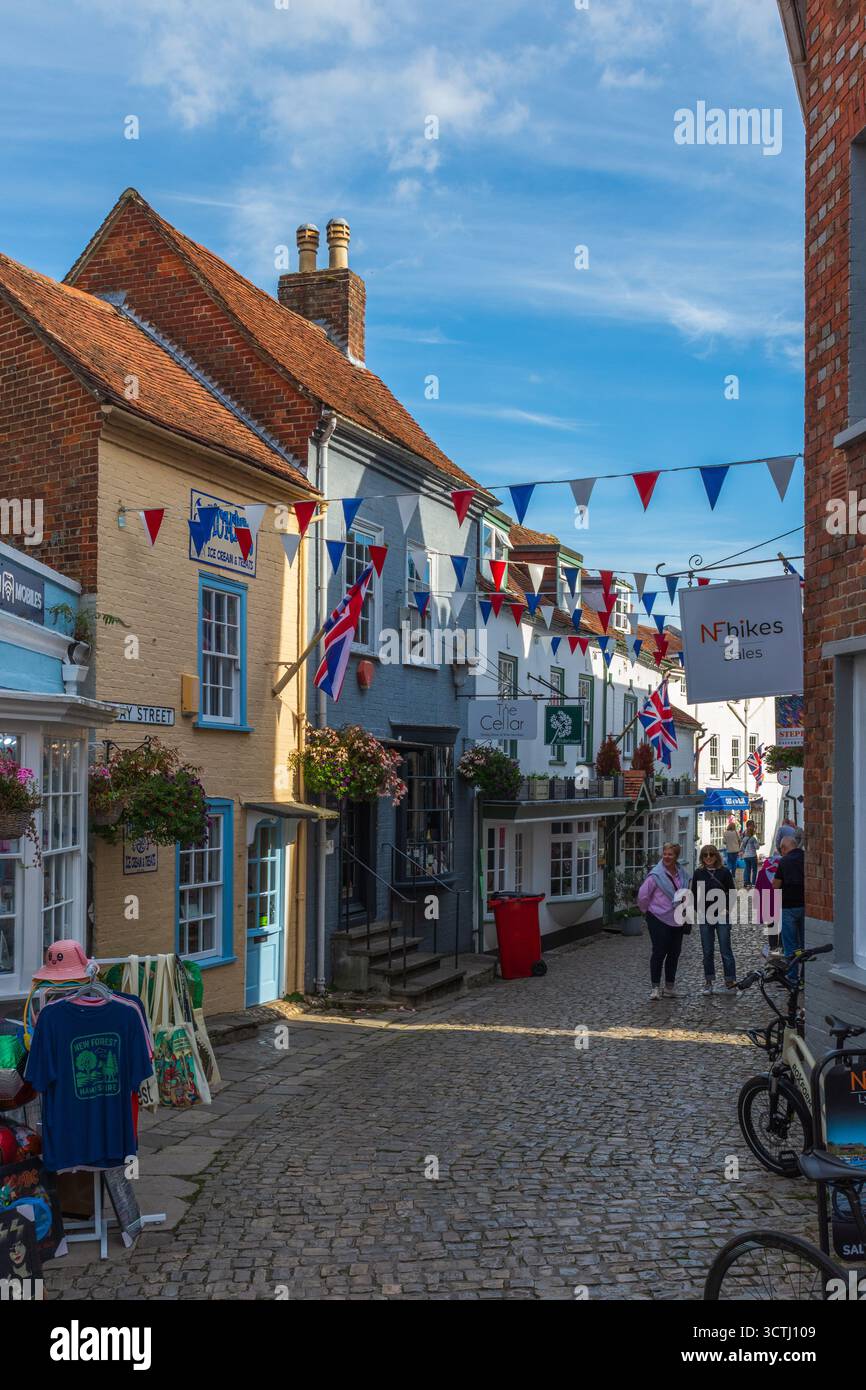 Quay Street, Lymington, Royaume-Uni - 29 septembre 2025 : People une rue de magasins dans des bâtiments classés grade II avec des banderoles et des drapeaux Union Jack. Banque D'Images