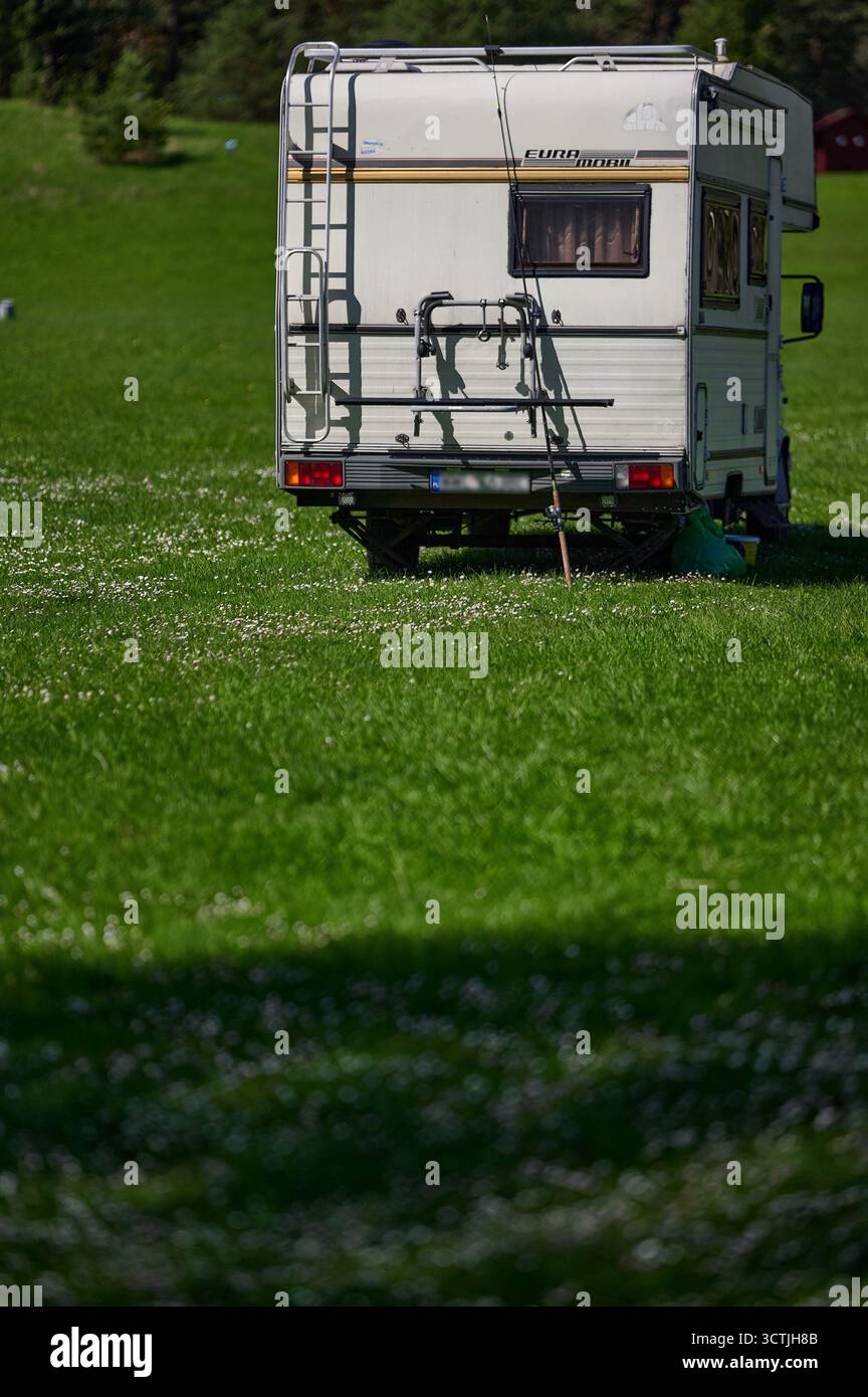 Vue arrière du camping-car sur terrain herbeux, orientation portrait, style brochure de voyage Banque D'Images
