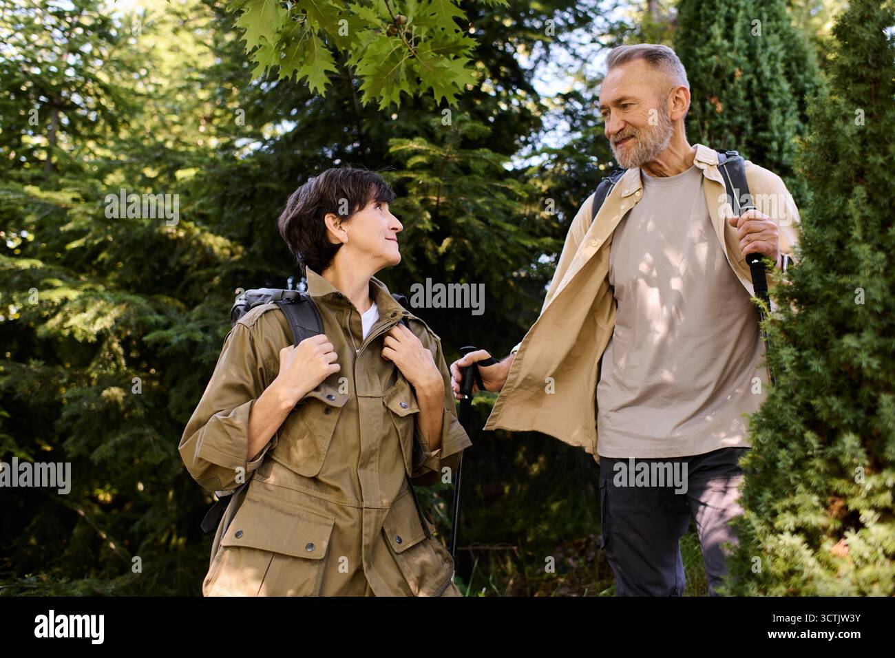 Un couple de personnes âgées actif explore la nature ensemble, partageant sourires et aventures dans les montagnes. Banque D'Images