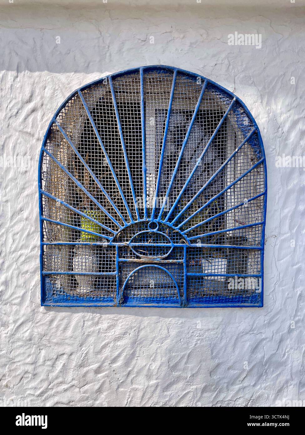 Grille décorative sur fenêtre voûtée sur mur texturé blanc, Martil, Tétouan, Maroc, 6 octobre 2025. Banque D'Images