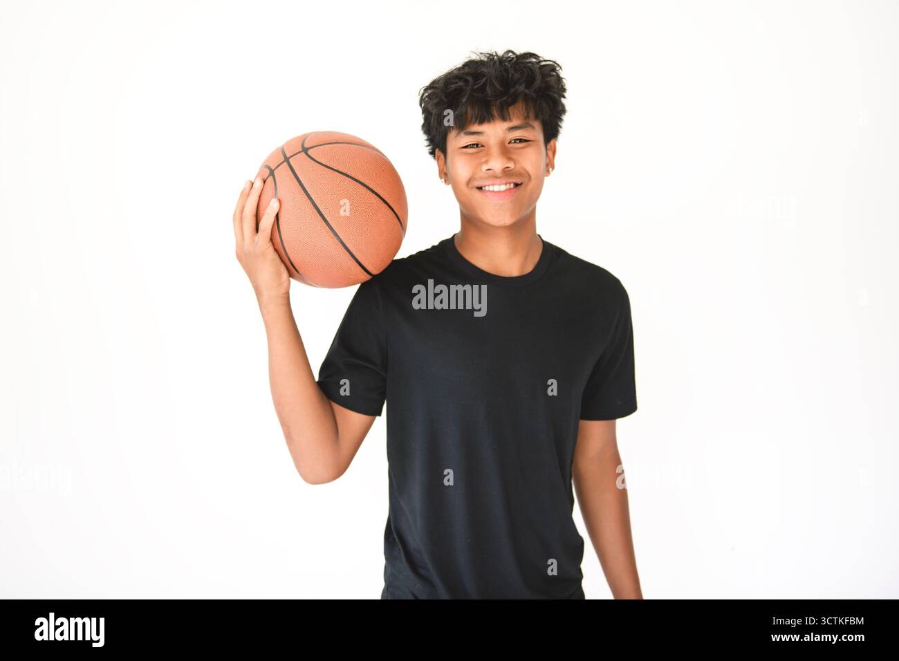 Un adolescent noir en sportswear jouant au jeu de basket-ball sur fond blanc de studio Banque D'Images