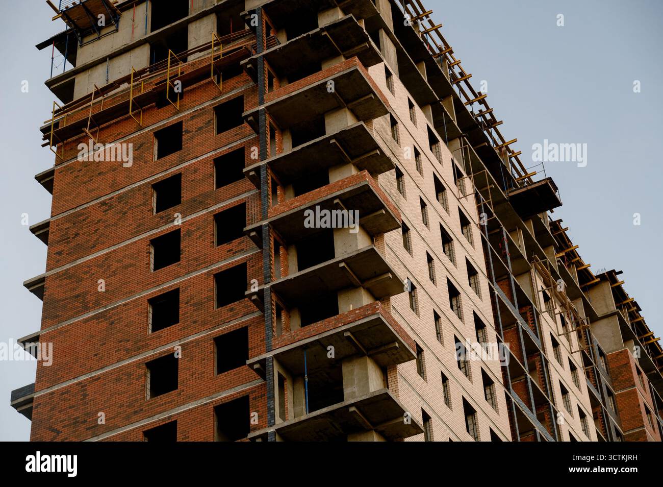 Un bâtiment résidentiel de plusieurs étages en construction en brique rouge et béton. Construction inachevée d'un immeuble de grande hauteur avec revêtement en briques Banque D'Images