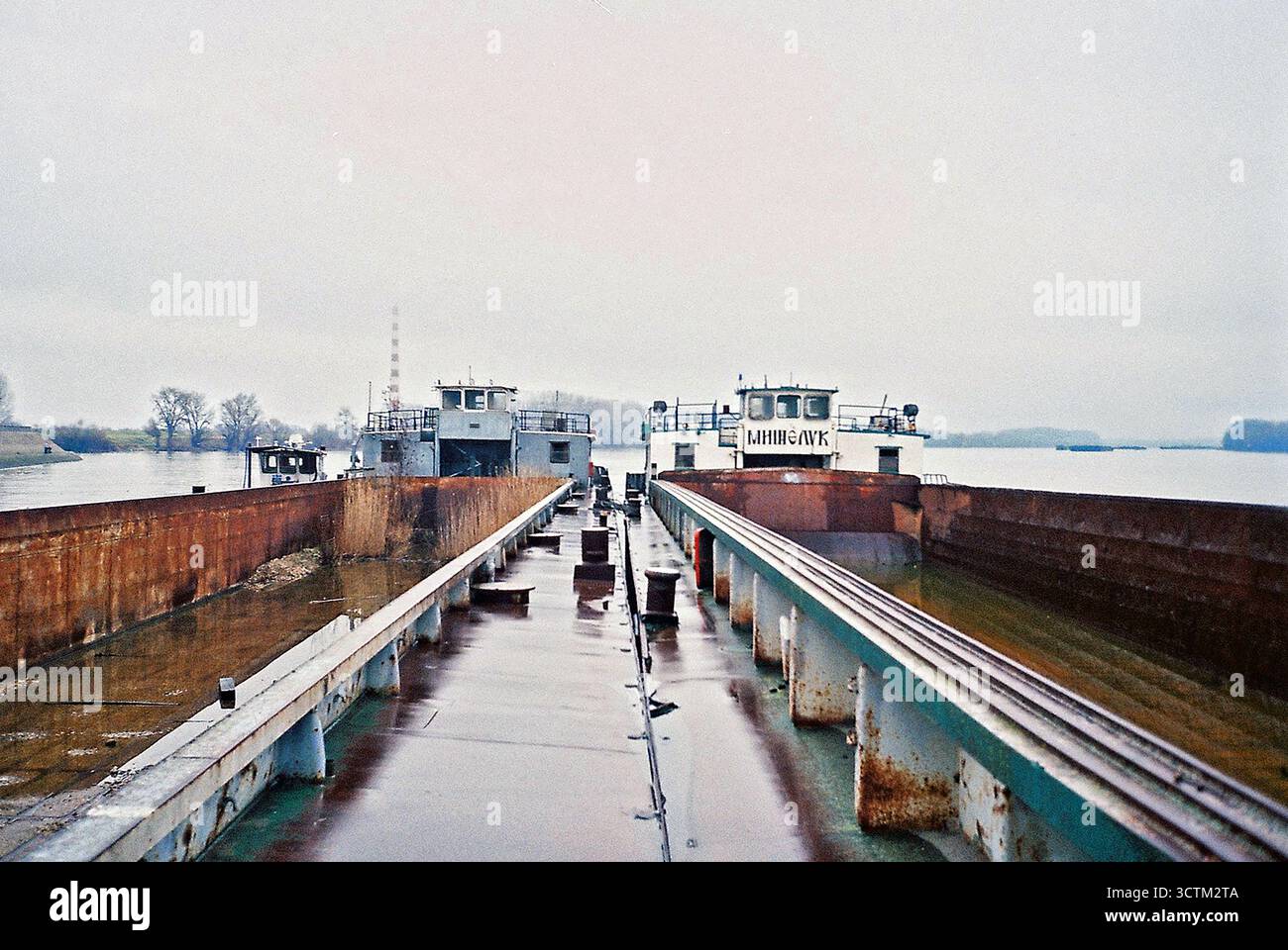 Deux cargos stationnés dans une composition symétrique par un jour nuageux et pluvieux, capturés dans un film analogique avec des textures de humeur changeante. Banque D'Images
