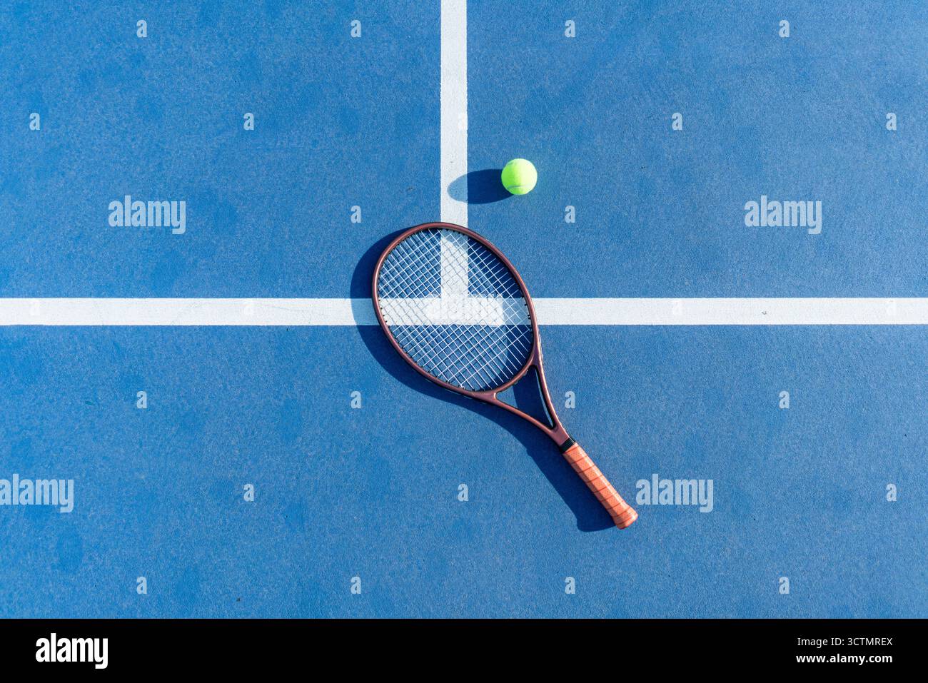 Vue en grand angle de la raquette de tennis avec balle sur la surface bleue du court Banque D'Images