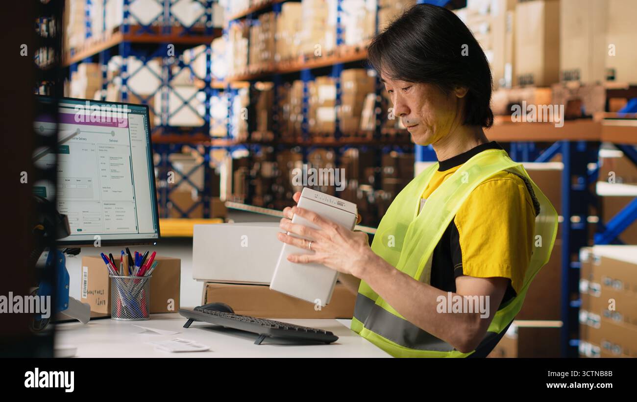 Le personnel du centre de distribution imprimant et appliquant des étiquettes awb sur les emballages, portant un gilet haute visibilité dans un entrepôt. Utilisation de la lettre de transport aérien à code-barres et des étiquettes d'expédition pour l'exécution et le suivi des commandes. Caméra B. Banque D'Images