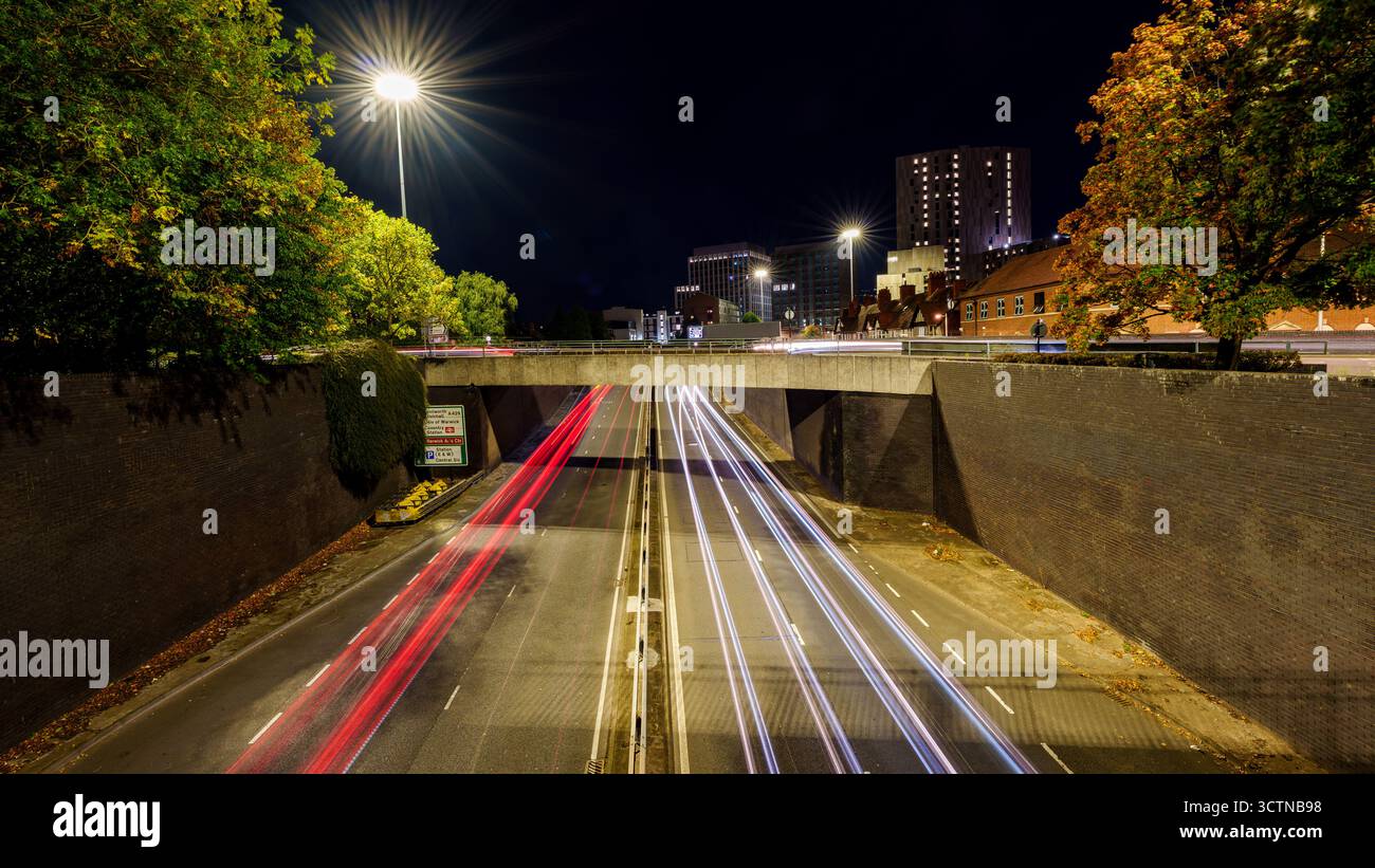 La circulation routière urbaine la nuit crée des traînées lumineuses vives, montrant la vitesse et le mouvement dans le paysage urbain moderne Banque D'Images