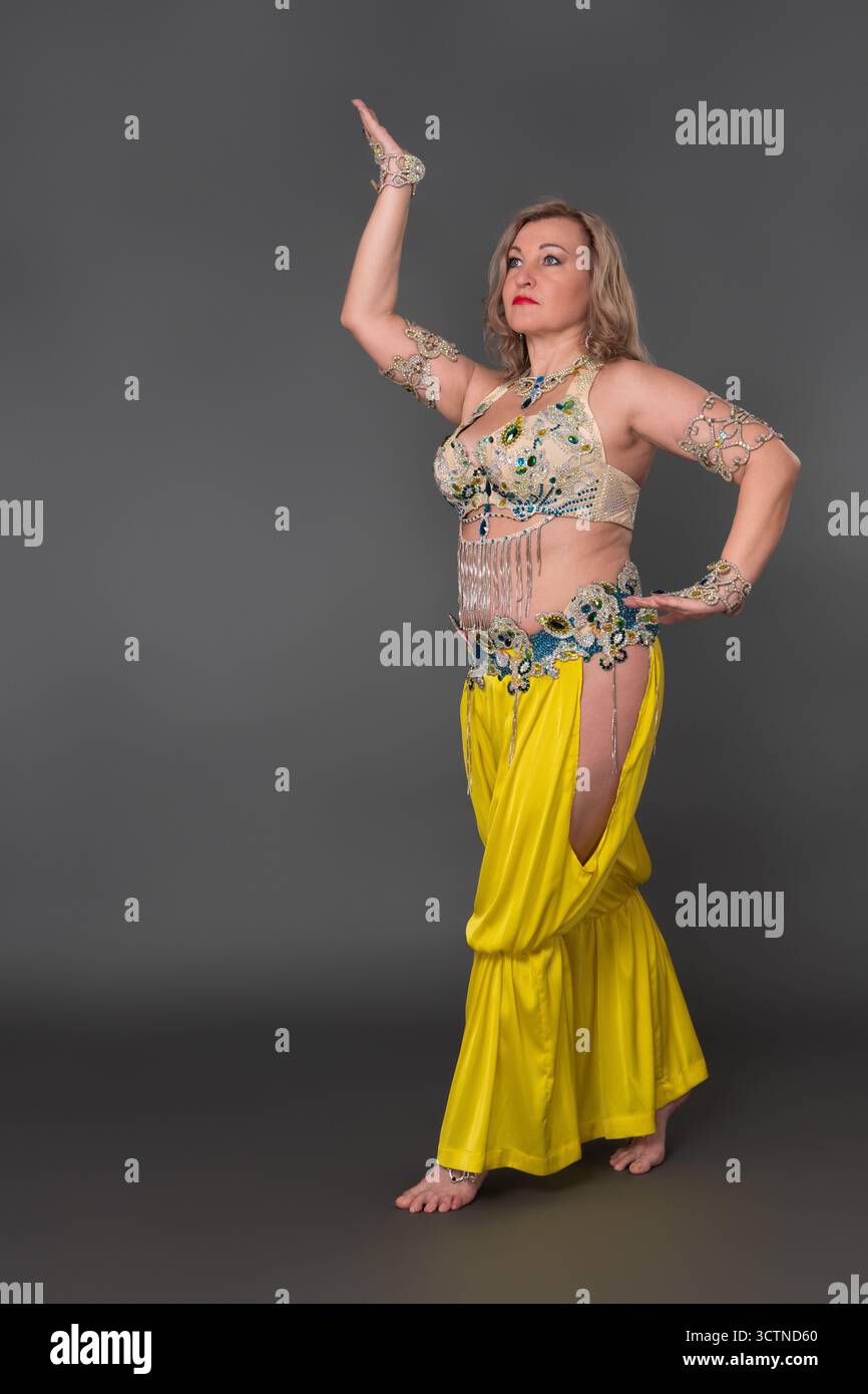 Confiance femme danseuse avec son habillage relevé à la main en costume de danse - haut et pantalon de harem jaune et elle ne porte pas de chaussures, performi Banque D'Images