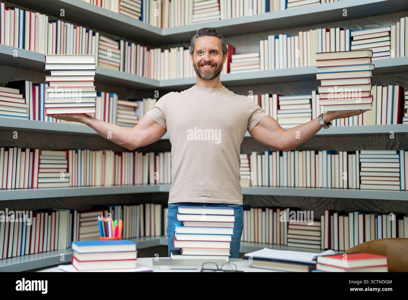 Portrait de professeur drôle avec livre dans la salle de classe de la bibliothèque. Beau professeur dans la bibliothèque universitaire. Professeur drôle tenir beaucoup de livres. Professeur fou avec Banque D'Images