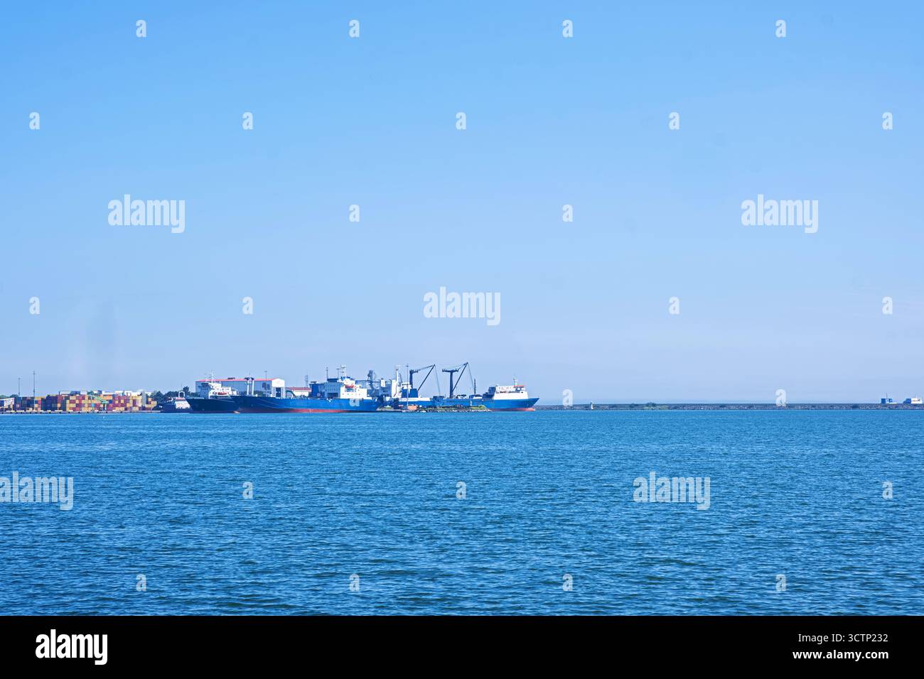 Cargos amarrés au port. Paysage marin industriel sous ciel clair. Un plan large à travers la mer capture plusieurs grands navires de cargaison et industriels amarrés à un Banque D'Images