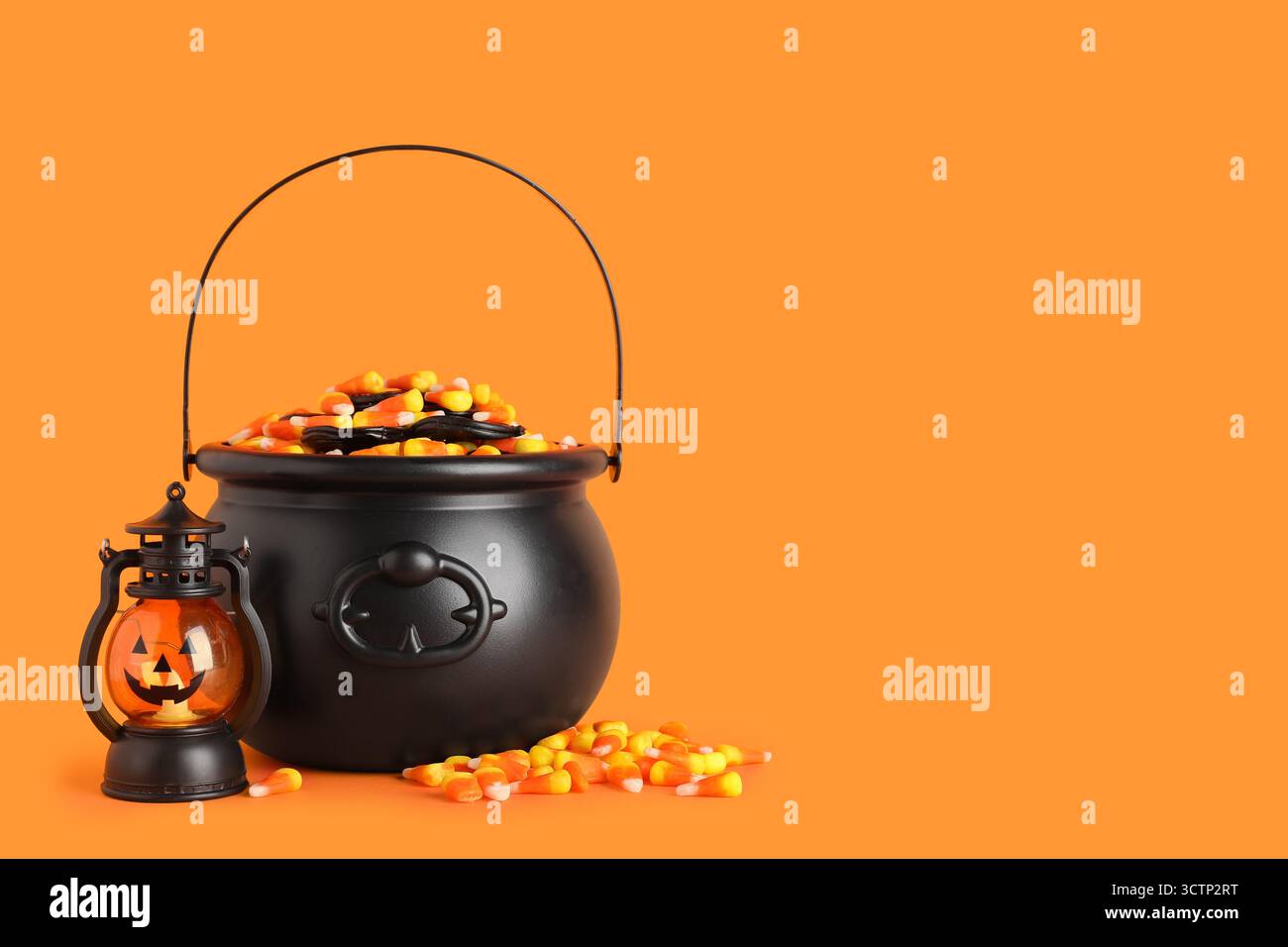 Chaudrons de savoureux cors de bonbons d'Halloween et lanterne sur fond orange Banque D'Images