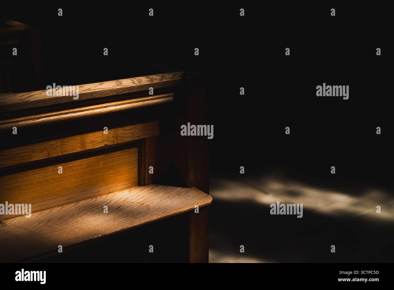 un rayon de soleil tombe sur un vieux banc en bois dans l'église Banque D'Images