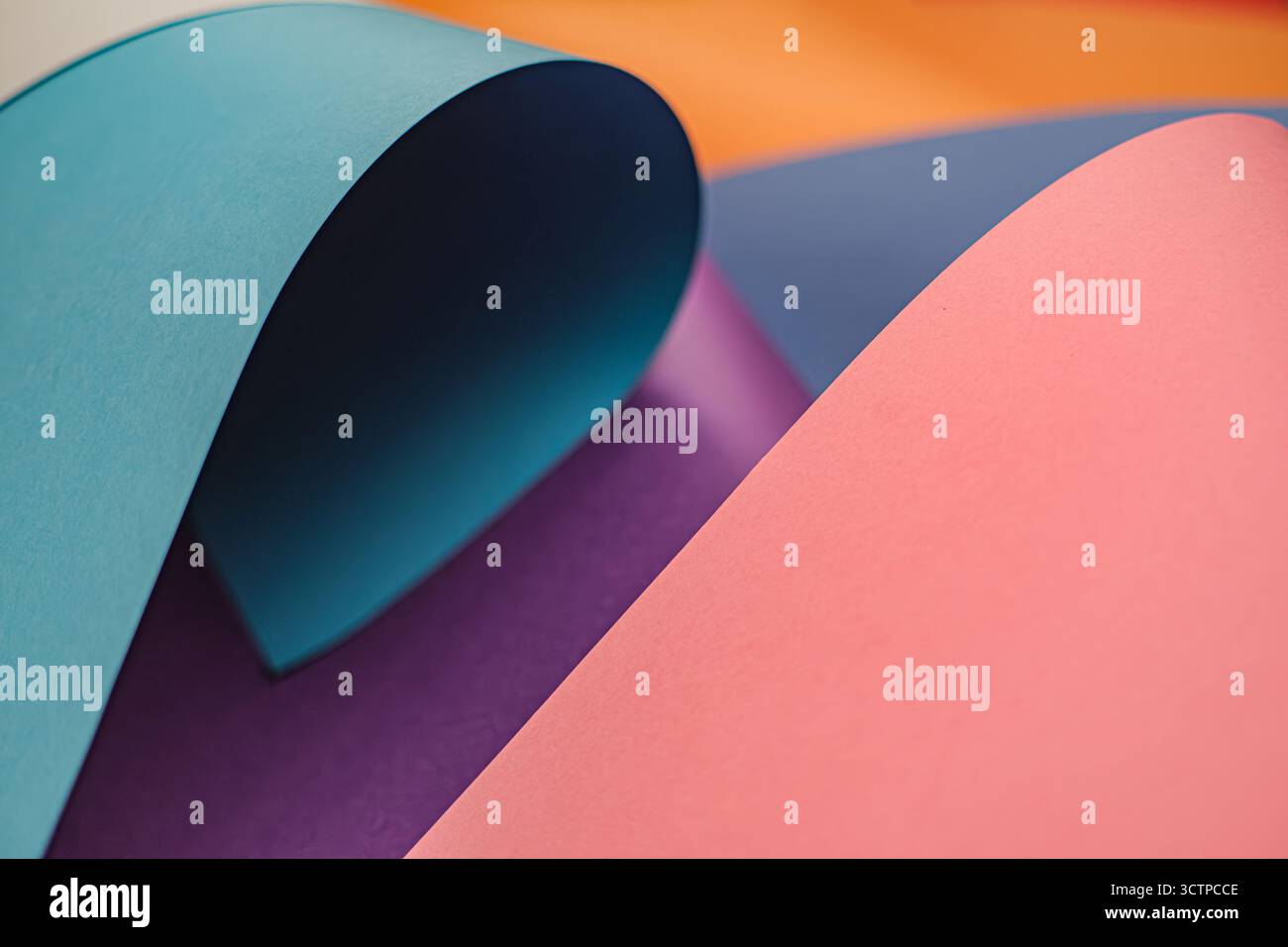 Composition abstraite de papiers courbes croisés en sarcelle, violet et rose. Créer des formes et des ombres dynamiques, évoquant un sentiment de fluidité et de mode Banque D'Images
