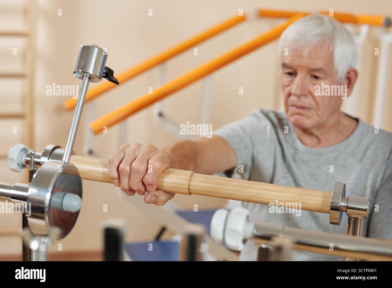 Homme caucasien senior faisant des exercices sur l'équipement de rééducation à l'hôpital tout en passant par la physiothérapie post-chirurgicale Banque D'Images