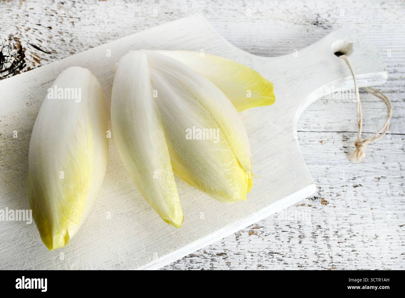 Endives belges crues fraîches (chicorée) isolées sur fond de bois. Nourriture saine et végétarienne. Directement au-dessus. Banque D'Images