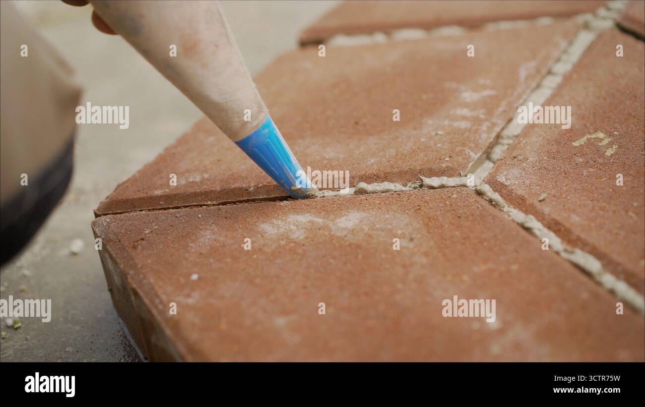 Scellement des joints de pavage avec du mortier. appliquer de la colle sur les coutures. Pose de pavés, fermeture des coutures. Banque D'Images