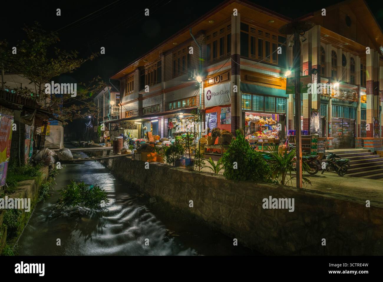 Scène de marché nocturne à Hsipaw Myanmar avec des reflets illuminés de rue et de canal – photographie de voyage éditoriale Asie Banque D'Images