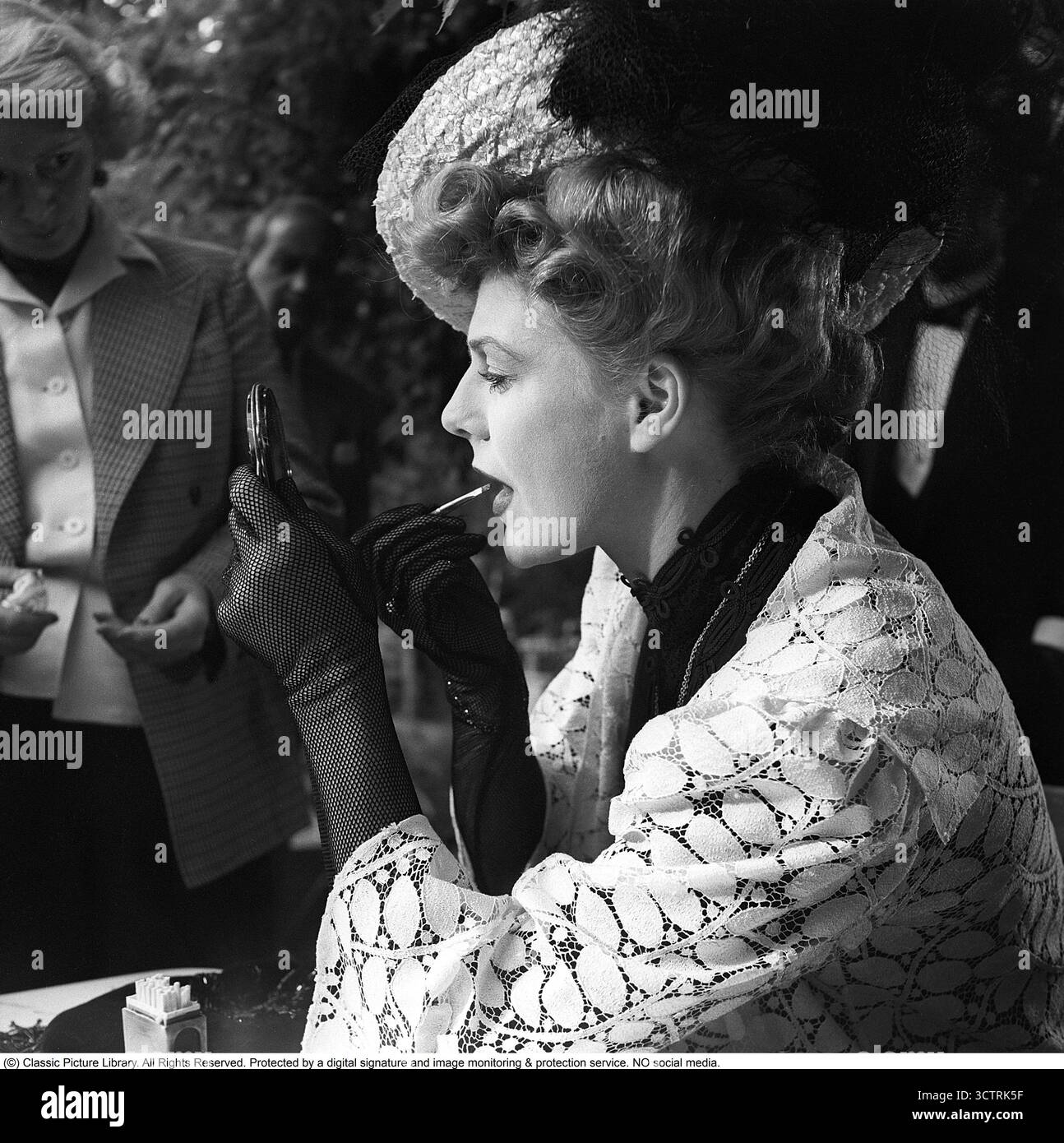 Long métrage När syrenerna blomma lors du tournage en 1952 à Nackanäs Värdshus. Maj-lis Lüning (1919–2010), dans le rôle de Julia, la femme fatale du film, retouche son maquillage avant une prise avec du rouge à lèvres, un produit qui rehausse les lèvres sans être un rouge à lèvres traditionnel. Suède, 1952. Kristoffersson réf. AZ37-4. Banque D'Images
