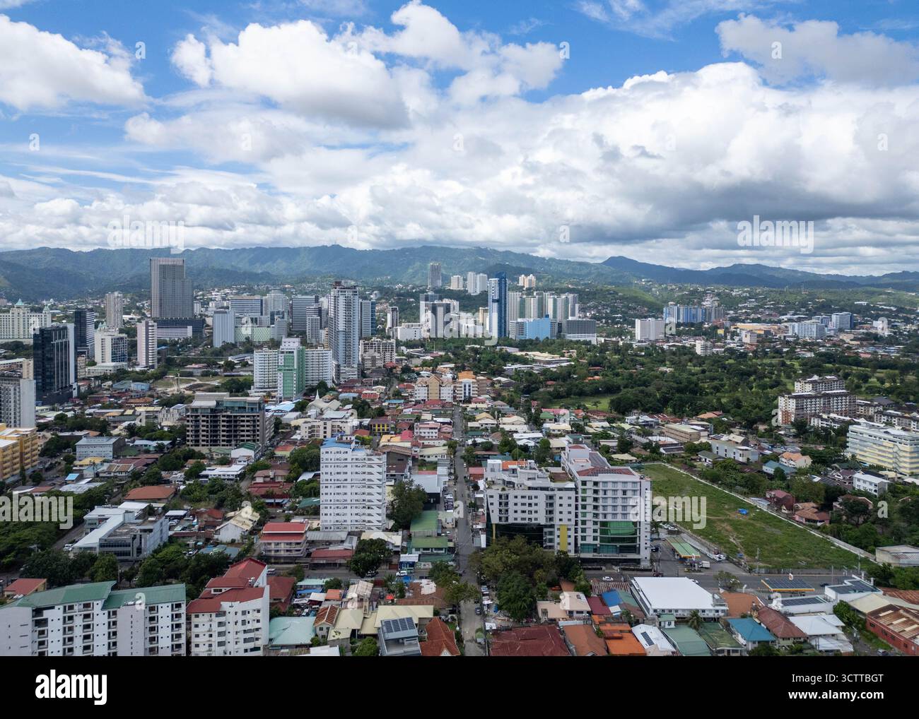 Vue aérienne des bâtiments et des maisons contrastant avec le feuillage vert, et le ciel avec des nuages blancs au-dessus, Cebu City, Visayas centrales, Philippines. Banque D'Images