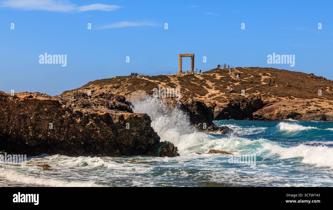 des vagues brisantes s'écrasent contre des rochers sombres devant la porte géante portara un monument grec ancien d'un temple à apollon sur naxos Banque D'Images