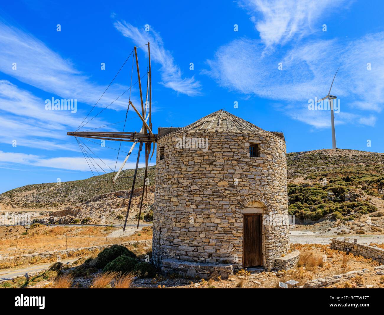 un moulin à vent en pierre grec traditionnel dans les montagnes de naxos en face d'une éolienne moderne au sommet de la colline énergie verte ancienne et nouvelle Banque D'Images