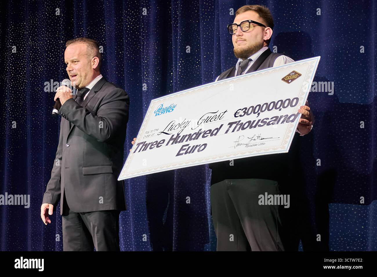 Venise. Italie - 08 octobre 2025 : un homme détient un chèque de prix géant de 300 000 euros pour un invité chanceux de Paradise Lotto lors d'une cérémonie de remise des prix. Banque D'Images