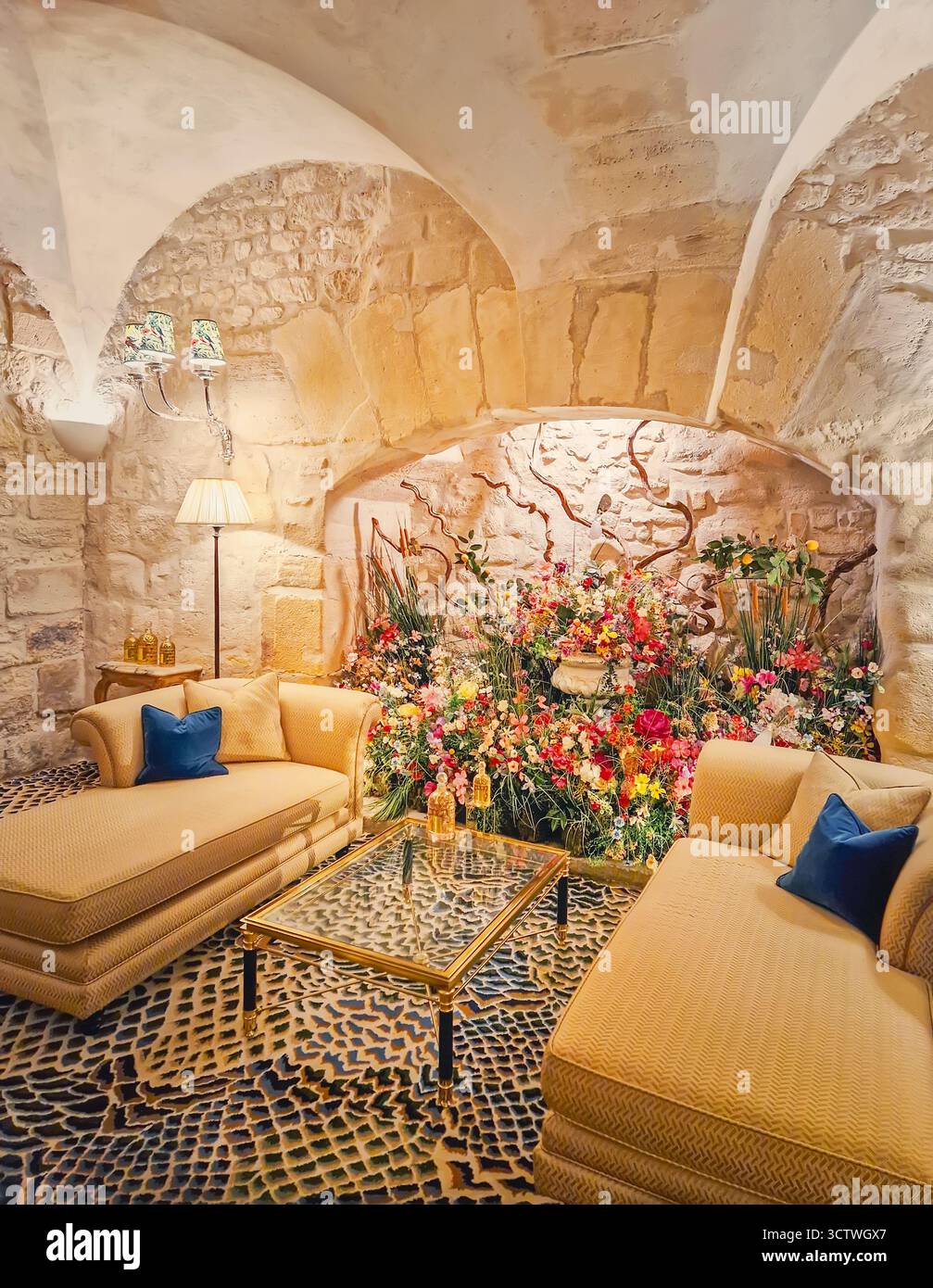 Intérieur confortable et atmosphérique avec des murs en pierre brute, chaises longues beiges luxueuses et une table basse en verre sur un tapis à motifs, et un remplissage d'alcôve Banque D'Images