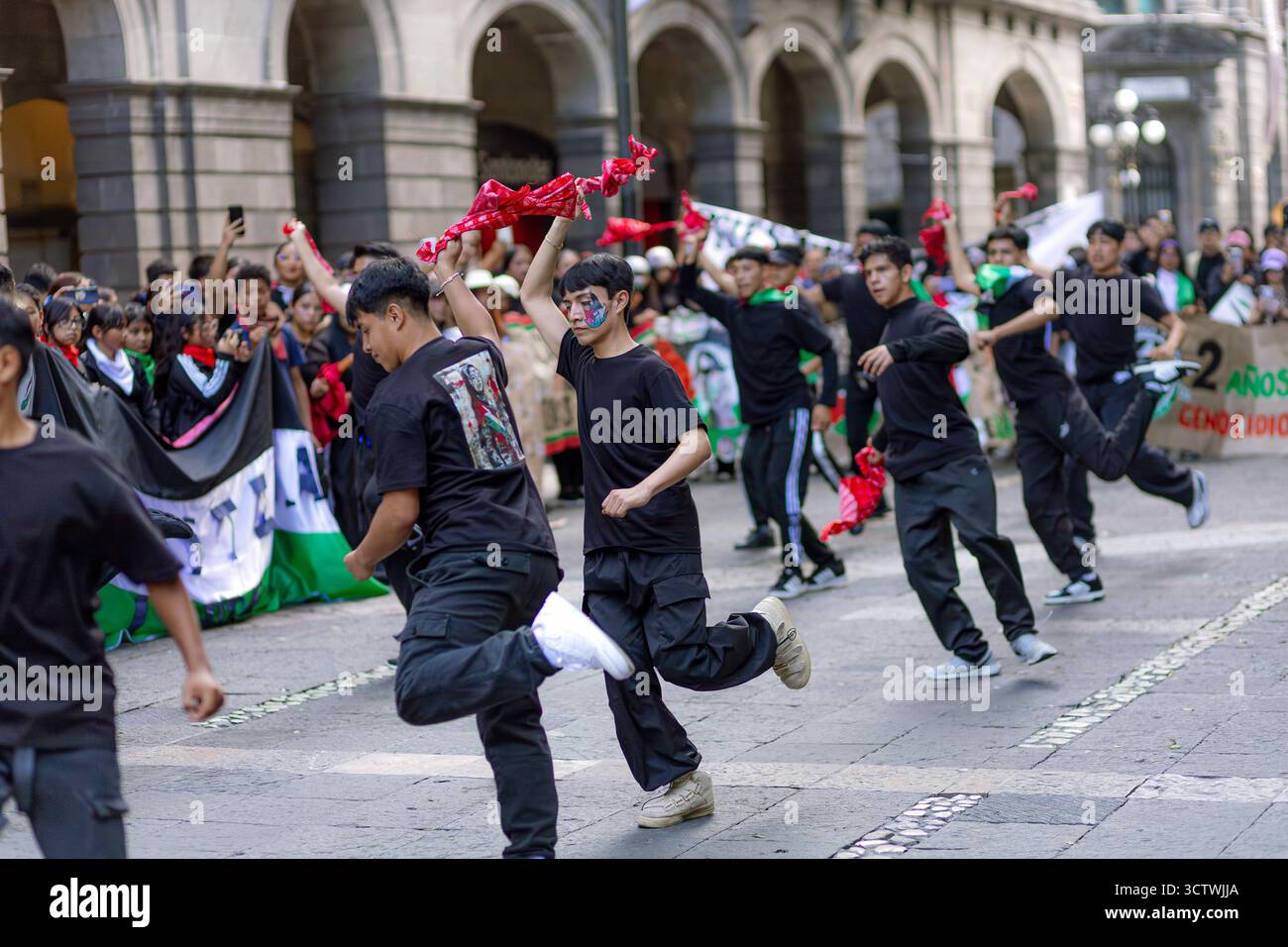 Un jeune manifestant souriant avec le drapeau palestinien peint sur son visage agite un tissu blanc lors d'une manifestation à Puebla. Banque D'Images