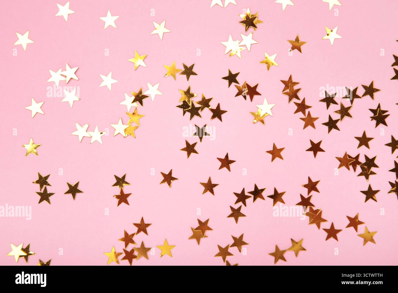 Étoiles de paillettes dorées sur fond rose. Vue de dessus Banque D'Images
