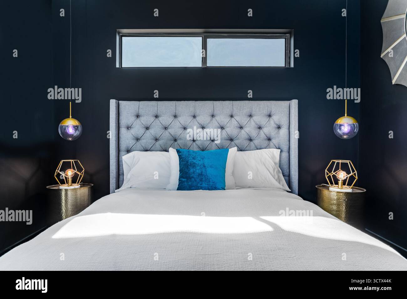 Intérieur moderne de la chambre à coucher touffeté gris lit accent oreiller murs noirs suspendus violets tables de nuit géométriques vue avant Banque D'Images