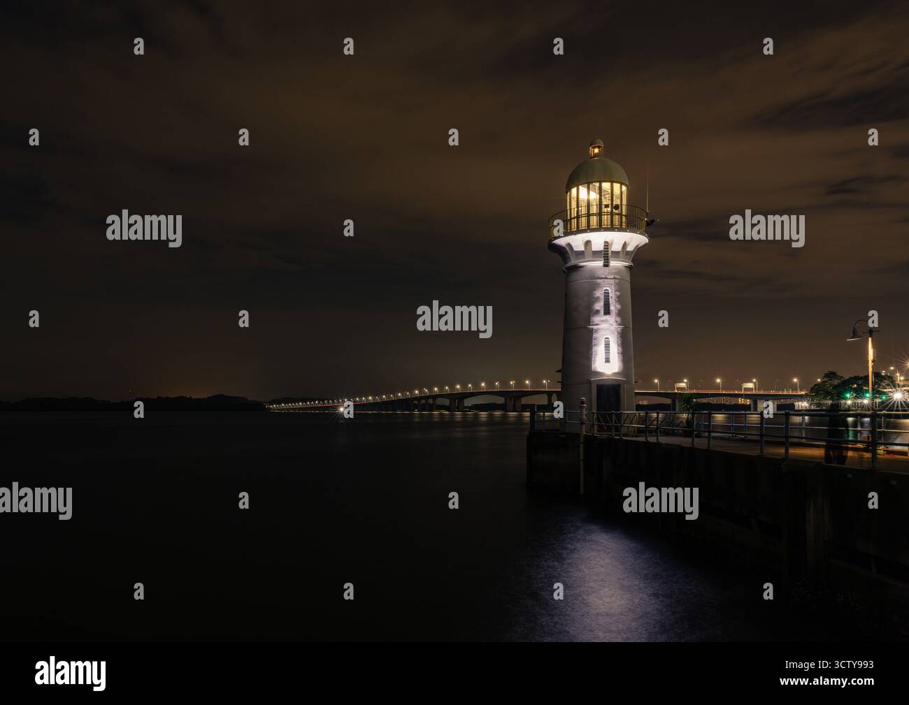 Longue exposition du phare de Raffles Marina à Singapour la nuit, avec le pont Tuas second Link vers la Malaisie illuminé en arrière-plan. Banque D'Images Longue exposition du phare de Raffles Marina à Singapour la nuit, avec le pont Tuas second Link vers la Malaisie illuminé en arrière-plan. Banque D'Images