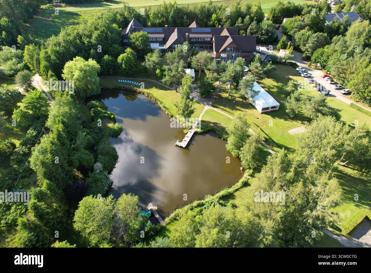 Hôtel de villégiature aérien avec lac forestier, Hôtel Kozi Grod Pomlewo, heure d'or d'été, tir de drone horizontal, composition à angle élevé pour brochure de voyage a Banque D'Images