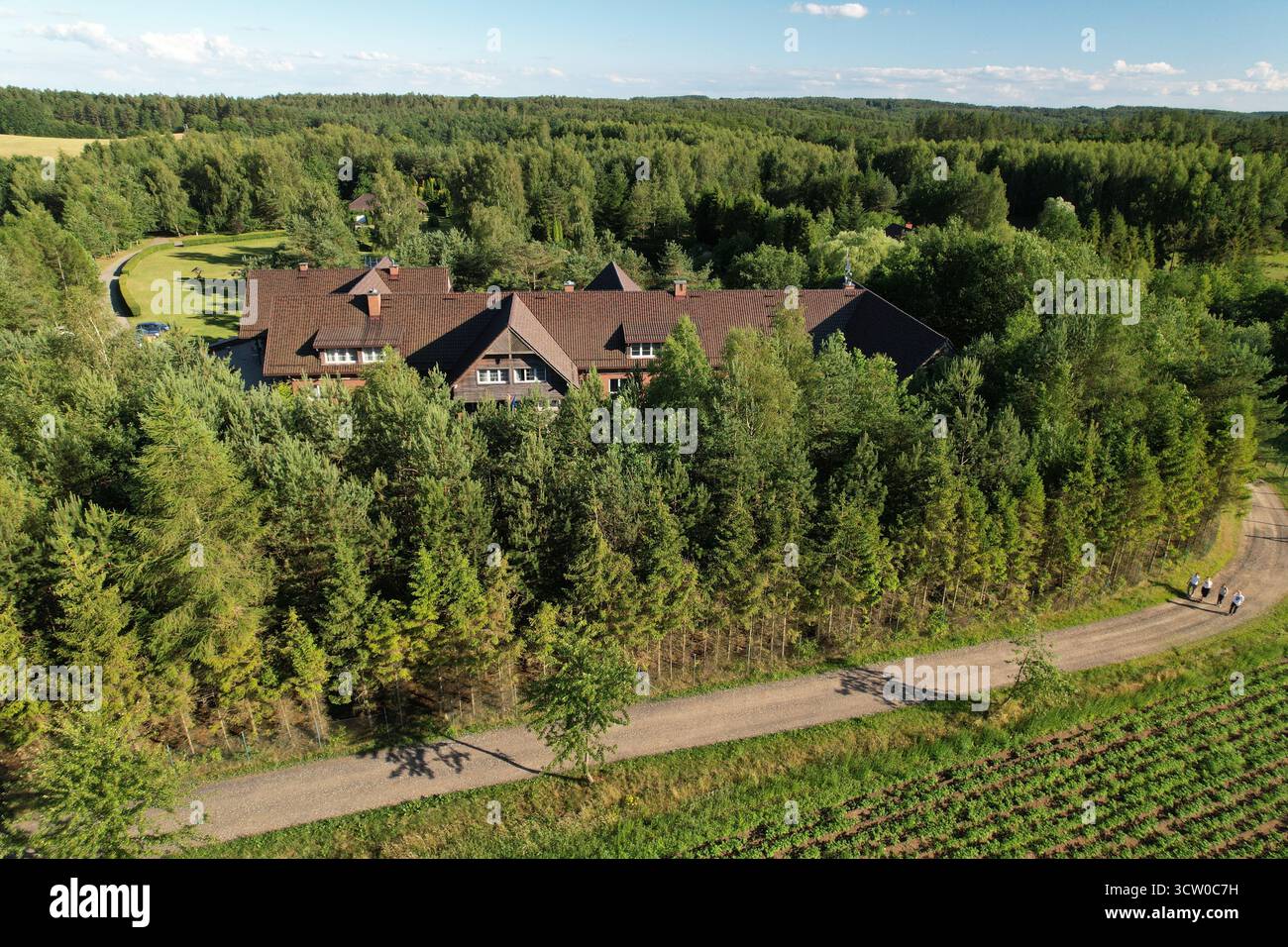 Hôtel aérien derrière conifère et route rurale, Hôtel Kozi Grod Pomlewo, heure d'or composition de drone horizontal avec ligne directrice pour la brochure de voyage an Banque D'Images