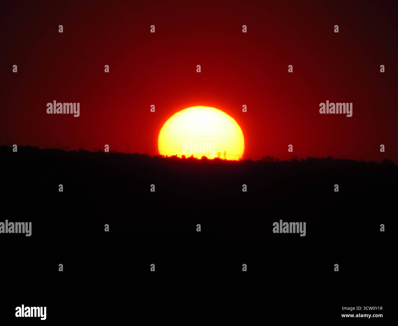 Un coucher de soleil spectaculaire sur le paysage sud-africain, avec de riches teintes orange et rouge illuminant l'horizon et le terrain silhouetté Banque D'Images