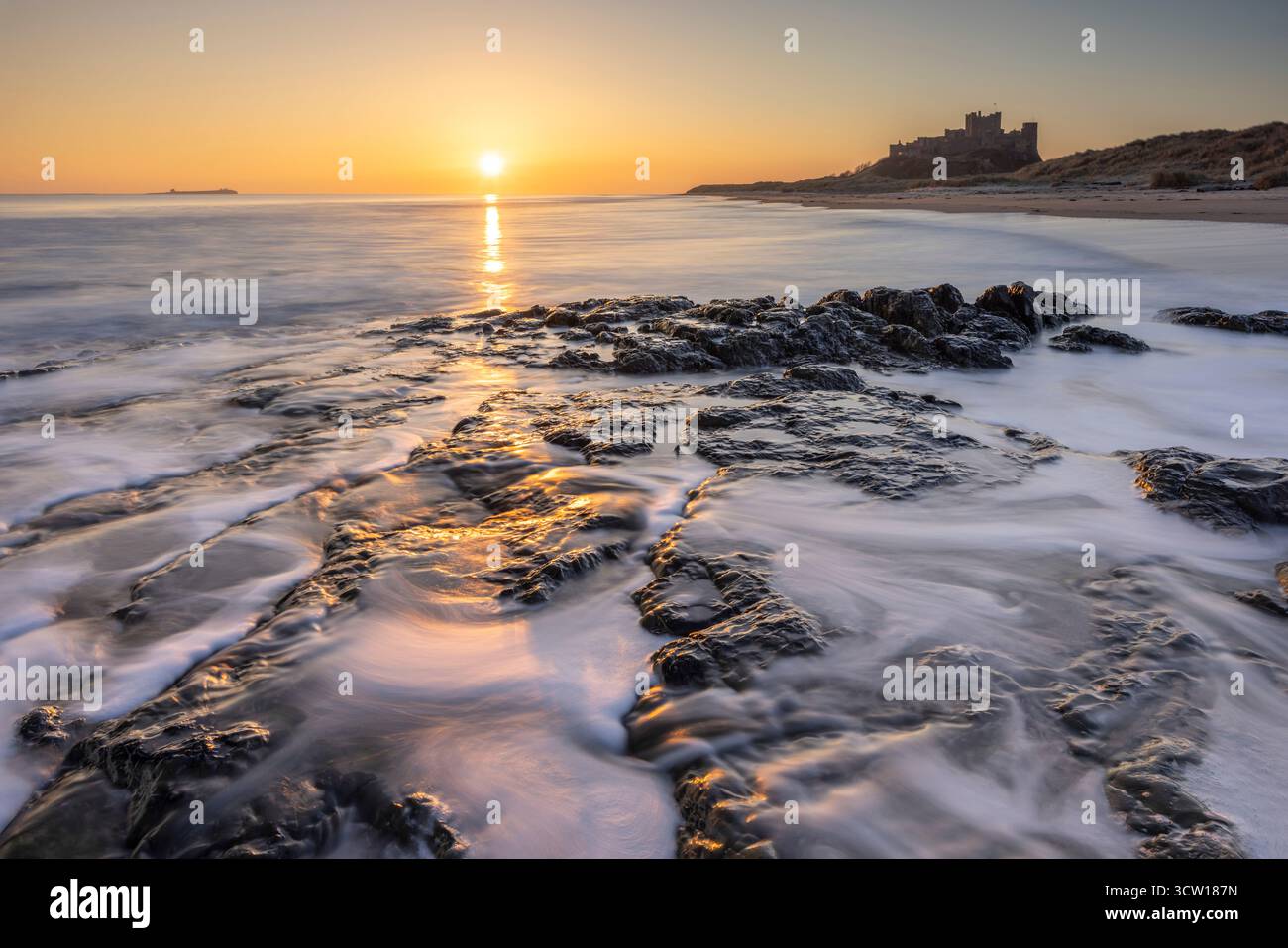 Lever du soleil sur le château et la plage de Bamburgh, Northumberland, Angleterre. Hiver (mars) 2025. Banque D'Images